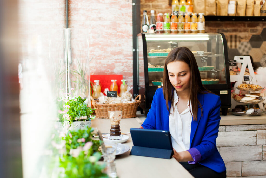 Woman Works With A Tablet At The Table In A Cafe - RW Office