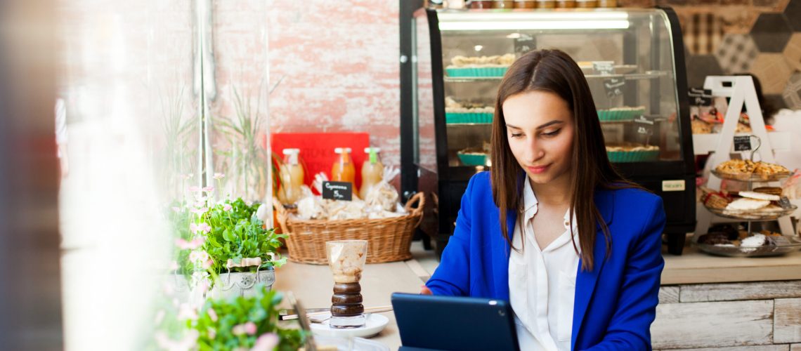 Woman Works With A Tablet At The Table In A Cafe - RW Office